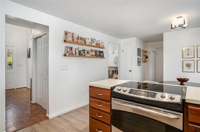 kitchen with brown cabinets, light countertops, baseboards, electric stove, and parquet floors
