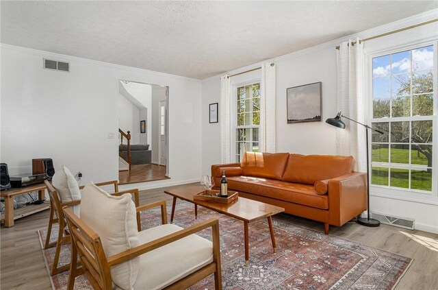 living area with visible vents, crown molding, stairs, wood finished floors, and a textured ceiling