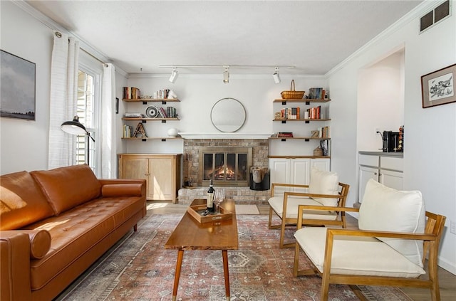 living room featuring a brick fireplace, visible vents, ornamental molding, and wood finished floors
