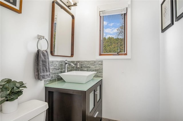 half bathroom featuring toilet, decorative backsplash, and vanity