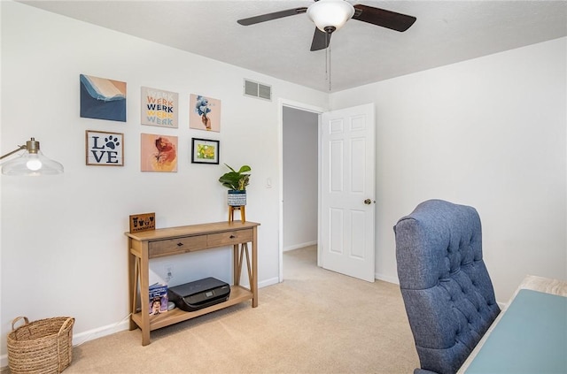 home office featuring visible vents, baseboards, ceiling fan, and light carpet
