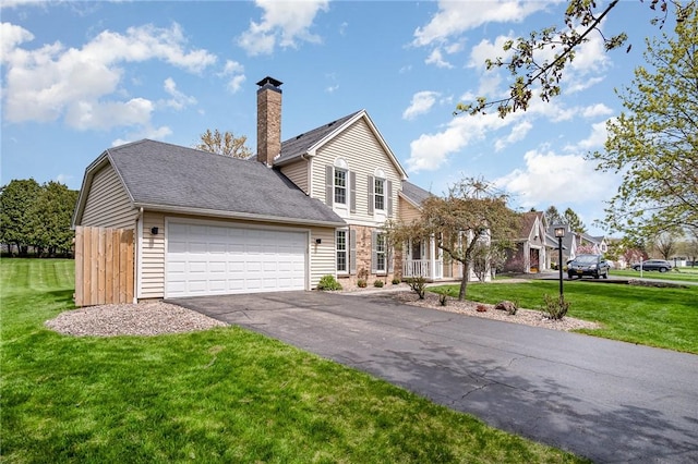 view of front of property featuring a garage, a front lawn, aphalt driveway, and a chimney