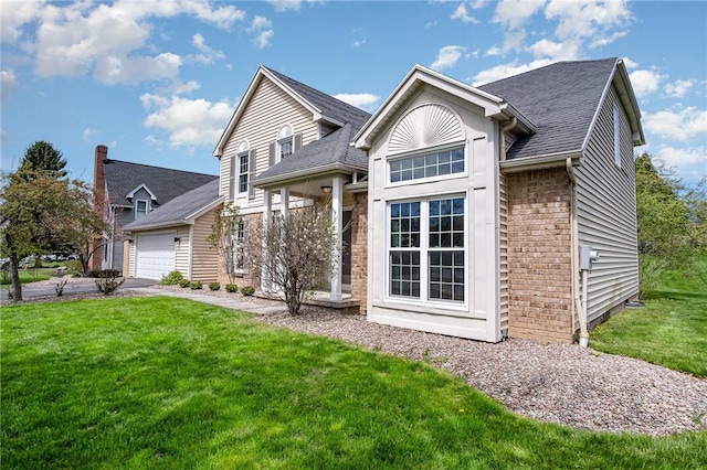 traditional-style home with brick siding, a garage, a front lawn, and driveway