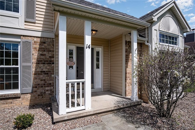 doorway to property with covered porch and brick siding