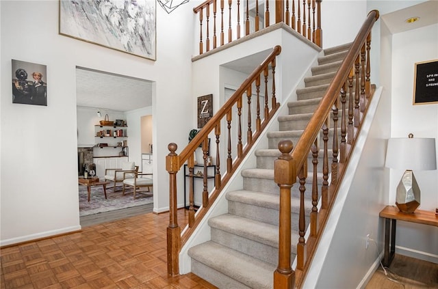 stairs with baseboards and a towering ceiling