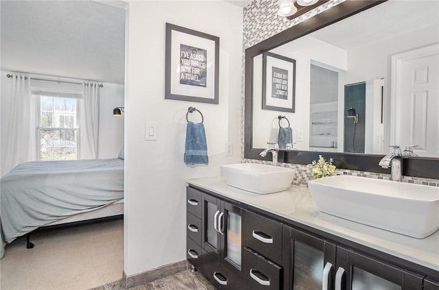 bathroom with a sink, baseboards, ensuite bath, and double vanity