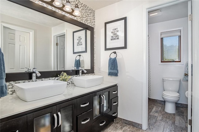 full bath with double vanity, a sink, wood finished floors, and toilet