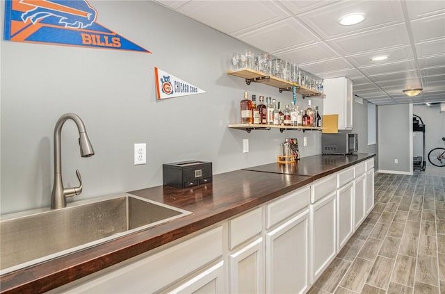 bar featuring recessed lighting, stainless steel microwave, a bar, a sink, and light wood finished floors