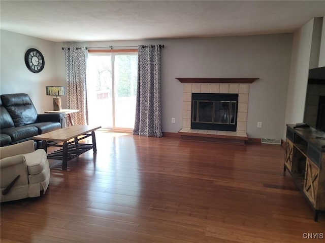 living area with visible vents, wood finished floors, and a tile fireplace