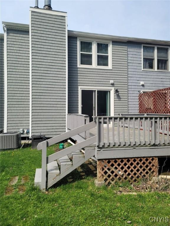rear view of house with a wooden deck, central AC unit, and a lawn