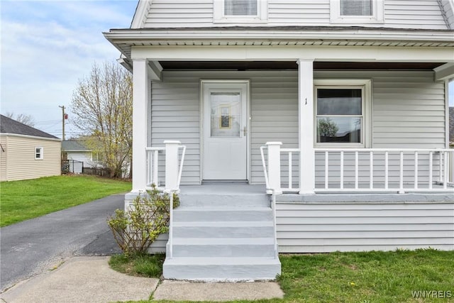 property entrance with covered porch and a lawn