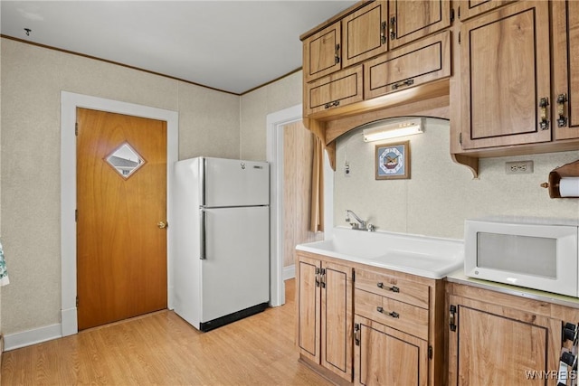 kitchen with brown cabinets, light wood-style floors, white appliances, light countertops, and ornamental molding