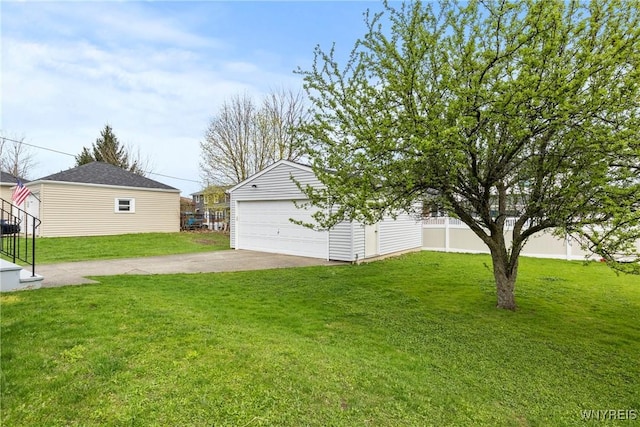 view of yard featuring a garage, fence, and an outbuilding