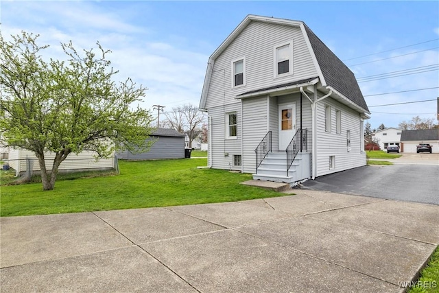 view of front of property with a shingled roof, a front lawn, a gambrel roof, and entry steps