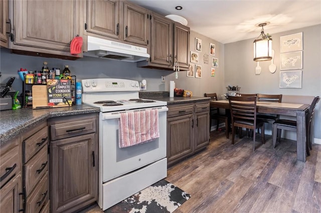 kitchen featuring wood finished floors, dark countertops, under cabinet range hood, white electric stove, and hanging light fixtures