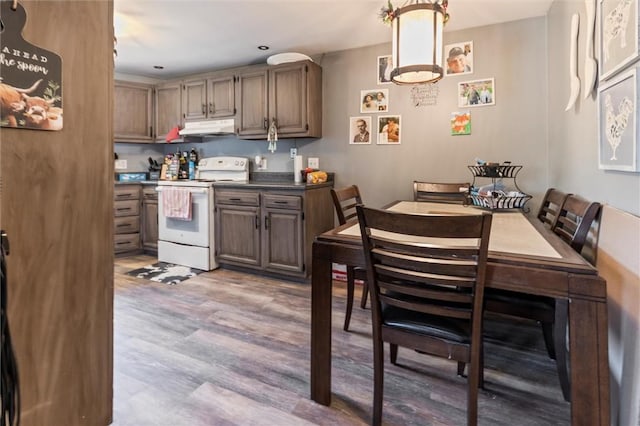 kitchen with white electric stove, dark countertops, recessed lighting, under cabinet range hood, and light wood-style flooring