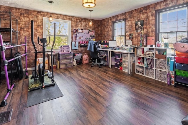 home office with a textured ceiling, visible vents, and wood finished floors