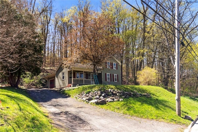 obstructed view of property with a porch, an attached garage, driveway, and a front yard