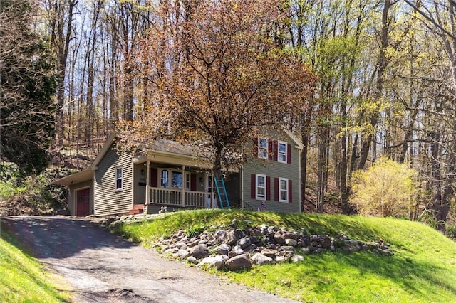 view of front of property with a porch, aphalt driveway, a front yard, and a garage