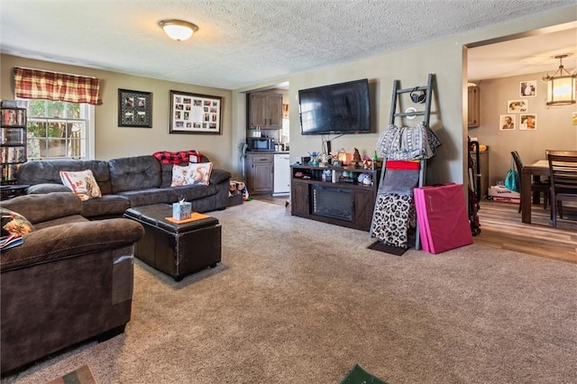 living room featuring a textured ceiling, carpet, and a notable chandelier