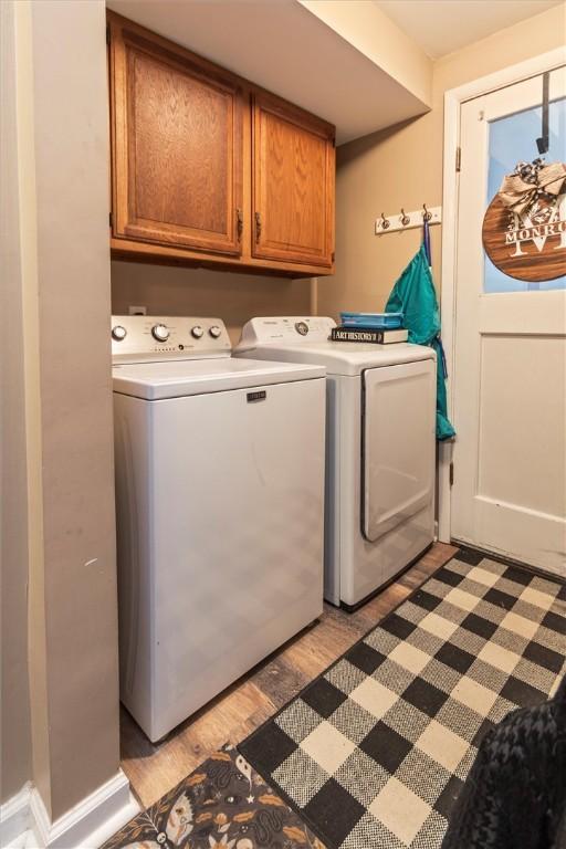 laundry area with light wood-type flooring, cabinet space, and washing machine and clothes dryer