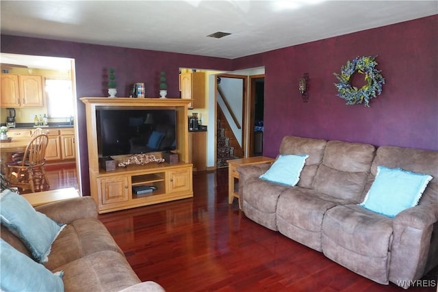 living room with stairs, dark wood finished floors, and visible vents