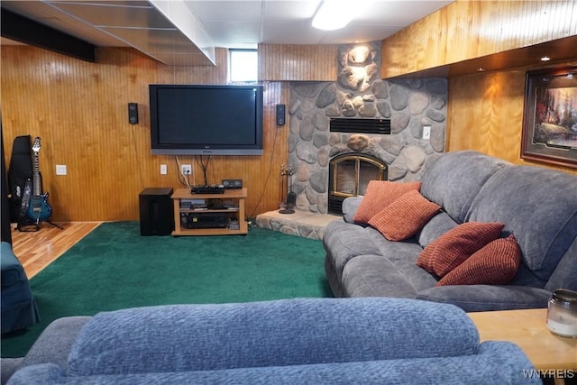 carpeted living area featuring wooden walls and a fireplace