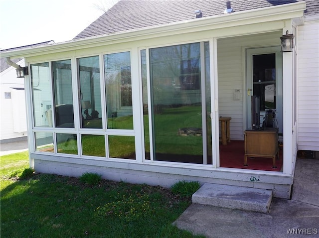 exterior space with a shingled roof and a sunroom