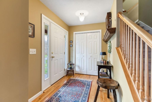 entrance foyer with baseboards, light wood finished floors, and stairway