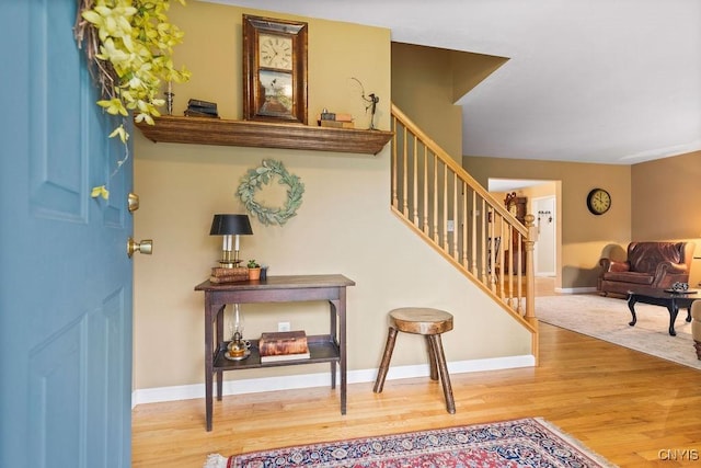 foyer entrance with baseboards, stairs, and wood finished floors