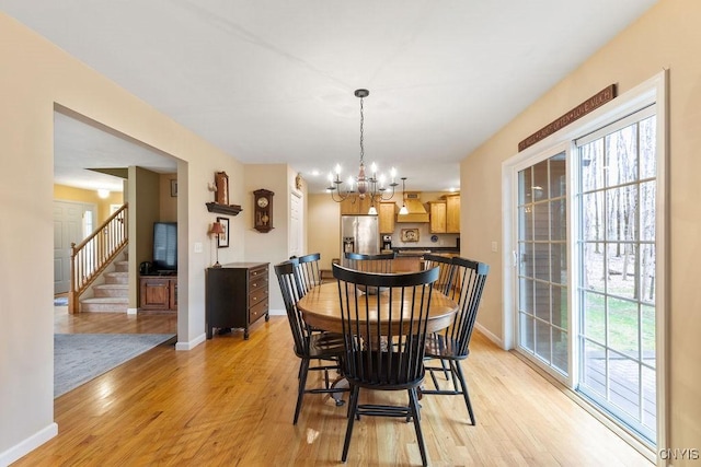 dining area with stairs, baseboards, a chandelier, and light wood-style floors