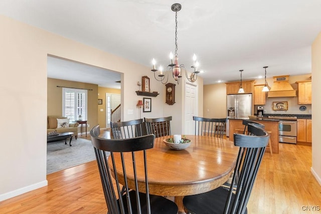 dining room with light wood-style floors, baseboards, and an inviting chandelier