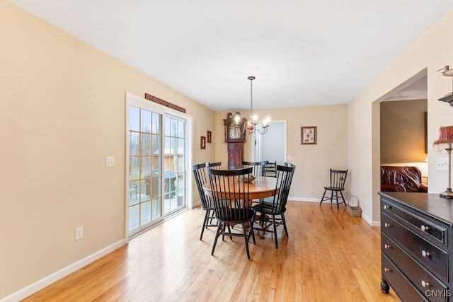 dining area featuring baseboards, light wood finished floors, and a notable chandelier