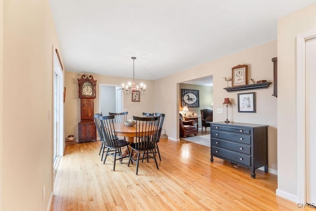 dining room featuring light wood-style floors, baseboards, and a notable chandelier