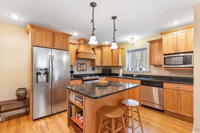kitchen featuring a sink, light wood-style floors, stainless steel appliances, a kitchen island, and custom exhaust hood