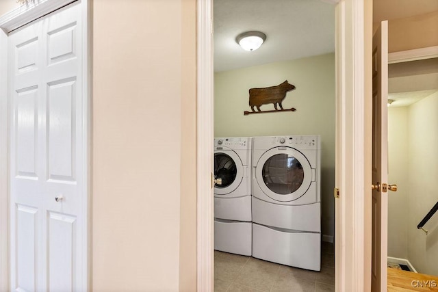 clothes washing area featuring laundry area, light tile patterned floors, and washing machine and dryer