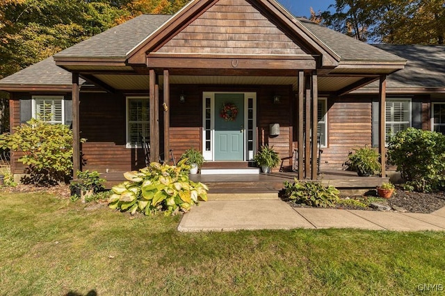 view of front facade with a porch, a shingled roof, and a front lawn