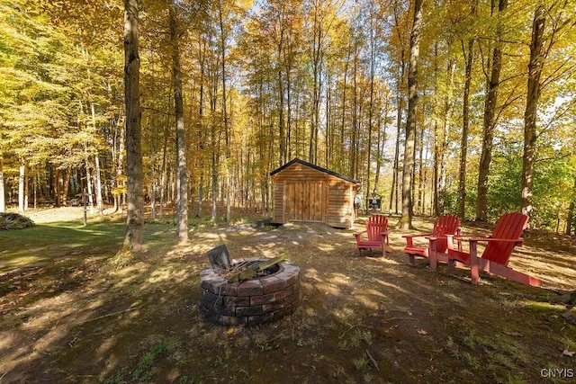 view of yard featuring an outbuilding, a fire pit, a shed, and a forest view