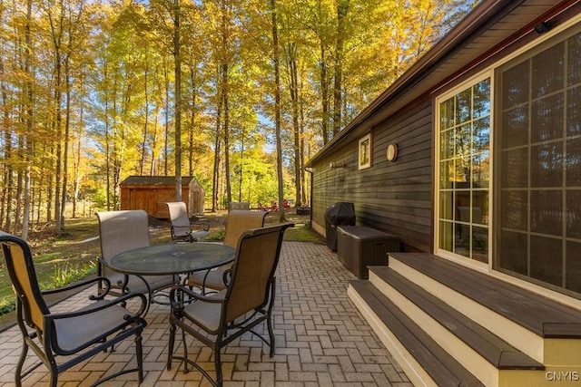 view of patio / terrace with a storage shed, an outdoor structure, and outdoor dining area