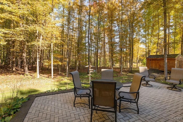 view of patio / terrace featuring a storage unit, an outdoor structure, and outdoor dining space