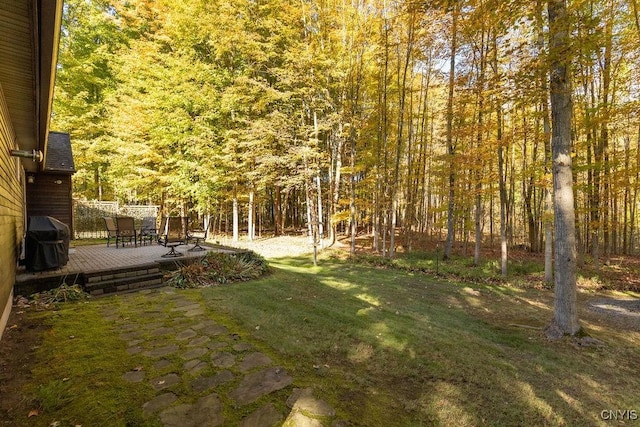 view of yard featuring a wooden deck and a forest view