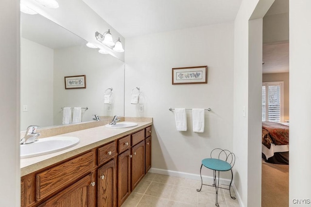 ensuite bathroom featuring double vanity, a sink, baseboards, and connected bathroom