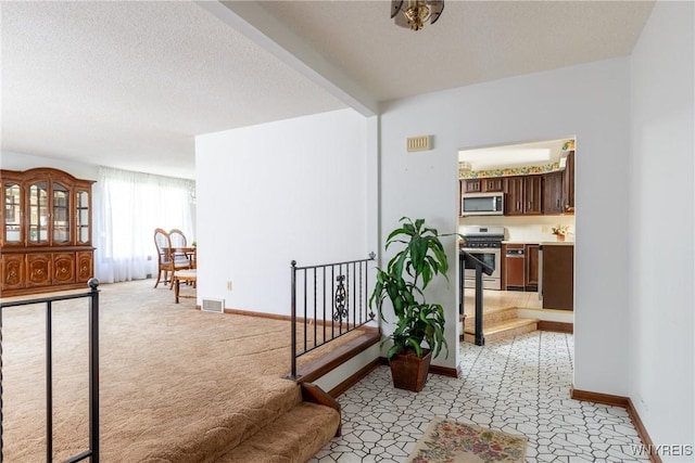 hallway with baseboards, light carpet, and visible vents