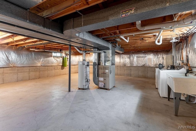 below grade area featuring water heater, heating unit, a sink, and washing machine and clothes dryer