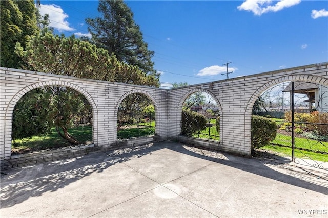 view of gate with fence and a patio area