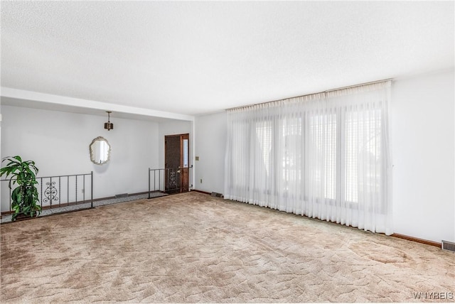 unfurnished living room with baseboards, carpet, and visible vents