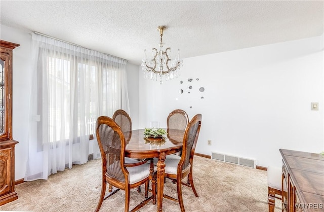 dining space featuring an inviting chandelier, light colored carpet, a textured ceiling, and visible vents