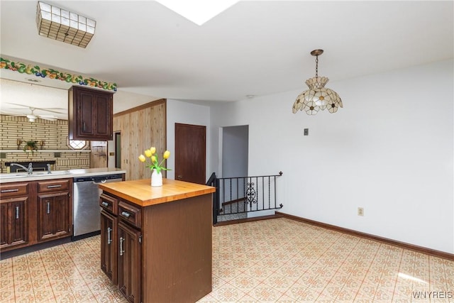 kitchen featuring pendant lighting, stainless steel dishwasher, a sink, baseboards, and butcher block counters