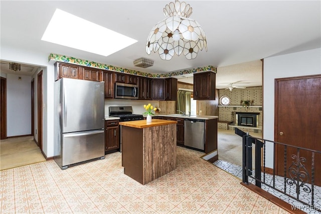 kitchen with a kitchen island, light colored carpet, wood counters, a skylight, and stainless steel appliances