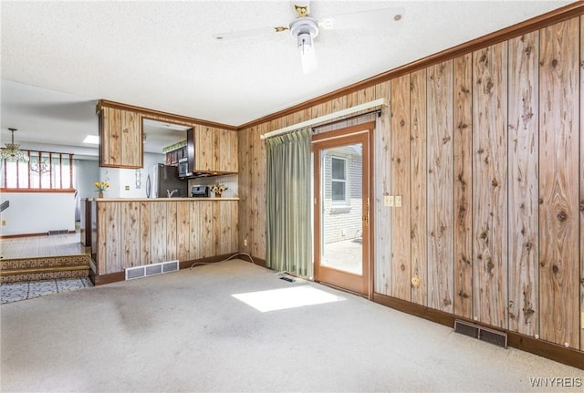 kitchen featuring carpet floors, wood walls, freestanding refrigerator, baseboards, and visible vents